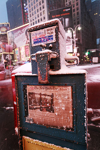 Week in Business: Snow falls on a New York Times vending box in Times Square