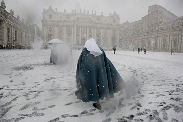 24 hours in pictures: A nun walks in St. Peter's square during a snow fall at the Vatican
