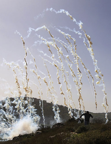 24 Hours in Pictures: A Palestinian demonstrator flees from tear gas fired by Israeli soldiers