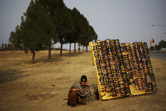 24 Hours in Pictures: A Pakistani vendor sits next to his sunglasses displayed for sale