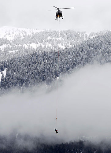 Winter Olympics day two: A rescue worker hangs from a helicopter near the finish line