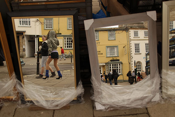 24 hours: Witney, England: Shoppers are reflected in mirrors on a market stall