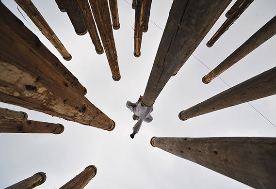 24 hours: Xiangfan, China: A man performs martial arts on the top of totem poles