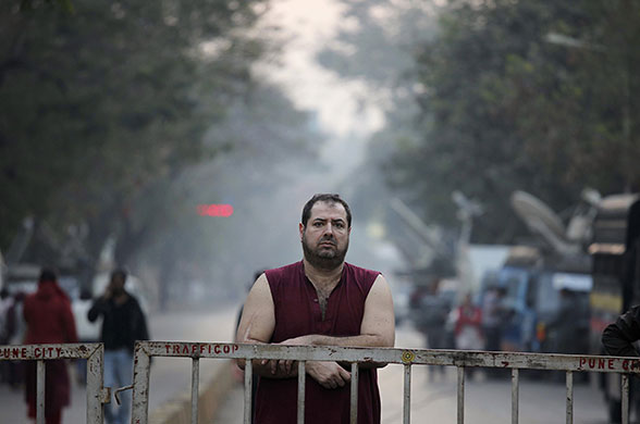 24 hours: Pune, India: A follower of Osho looks at the site of explosion