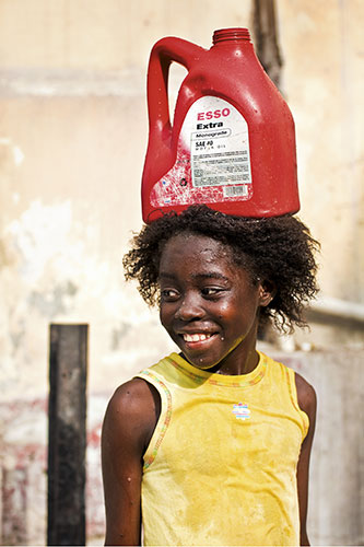 Haiti Exhibit Sale: Port-Au-Prince. Haiti: Girl carrying water in an oil can
