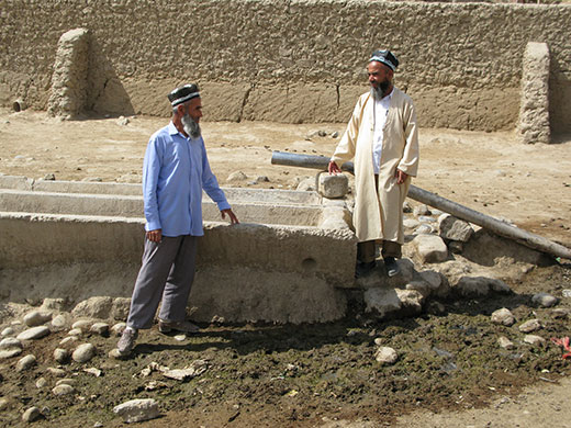 Tajikistan Climate: Two farmers standing by disused water point in Davat village Tajikistan