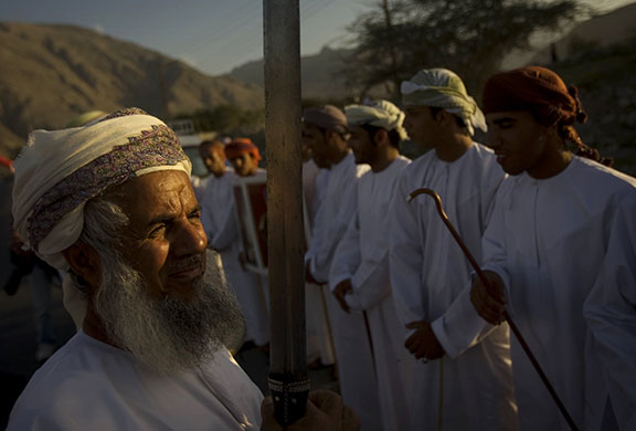 24 hours in pictures: Oman: A man holds a sword as he waits for cyclists 