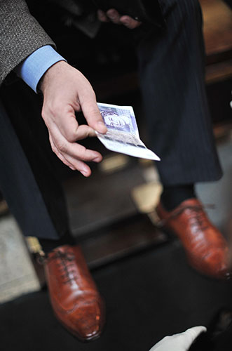 Week in business: A city worker produces a banknote after having his shoes shined in London