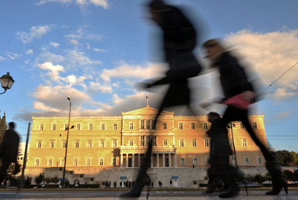 24 hours in pictures: Athens, Greece: People walk by the Greek Parliament