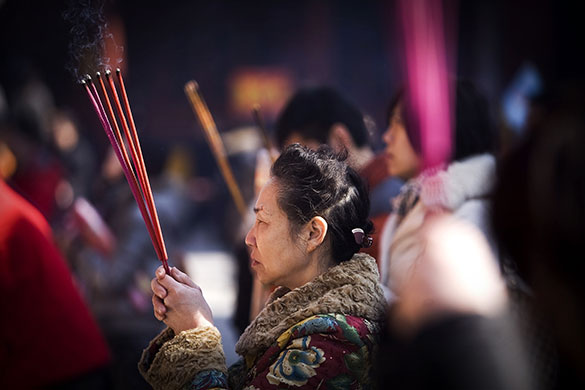 24 Hours in Pictures: People burn incense in prayer at the Lama Temple in Beijing
