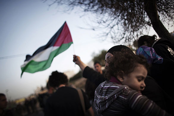 24 Hours in Pictures: A Palestinian woman waves her national flag while holding her sleeping baby