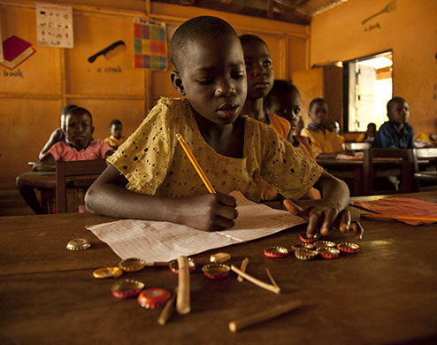 Ghana: A girl using bottle tops to count in a maths lesson at Brepaw Kpeti Presby