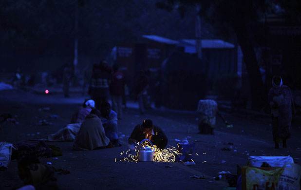 24 hours in pictures: New Delhi, India: A roadside tea vendor warms his kettle