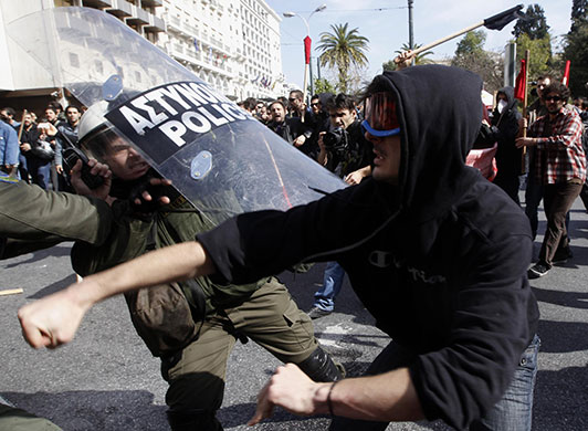 Clashes in Greece: A protester throws a punch at a police officer