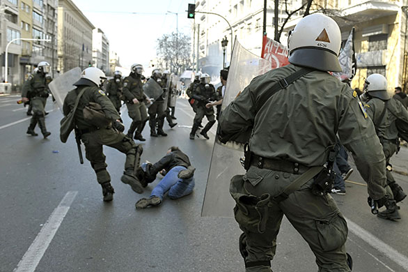 Clashes in Greece: A policeman kicks a demonstrator lying on the ground in Athens 