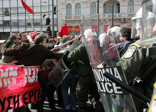 clashes in greece: Police officers clash with  people carrying a banner