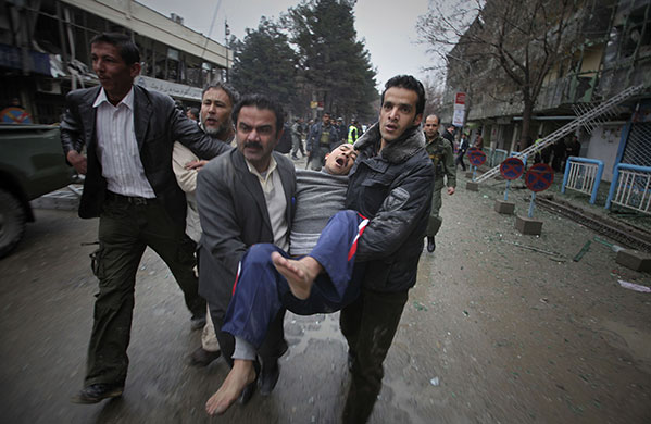 Kabul explosions: Afghans carry an unidentified man after he fled from a hotel 