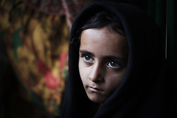 24 Hours in Pictures: A Pakistani girl waits for rice during a donated food distribution