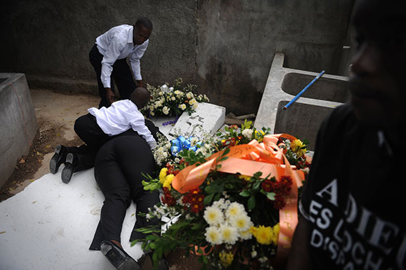 24 Hours in Pictures: A Haitian woman mourns at her husband's grave as her son consoles her