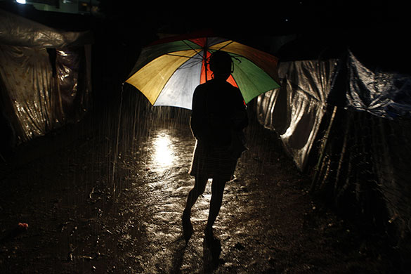 24 hours in pictures: A woman walks in rain homeless earthquake camp Port-au-Prince, Haiti 