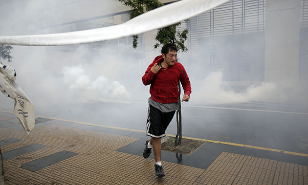 chile update: A man run away from tear gas, during looting in Concepcion, Chile