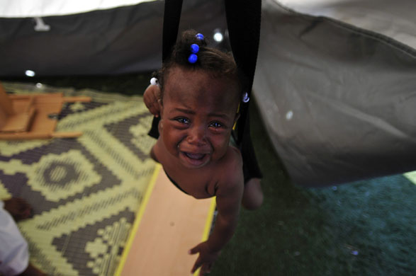 Haiti: A girl is weighed before receiving a vaccine at the National Stadium