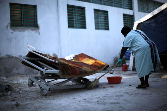 Haiti: A woman cleans under an empty bed at the general hospital in Port-au-Prince
