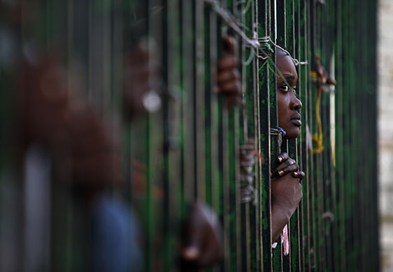 7 February 2010: Port-au-Prince, Haiti: A woman peers through the bars of a fence