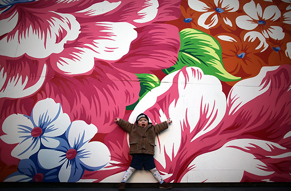 7 February 2010: Vancouver, Canada: A boy poses for his mother in front of a giant painting