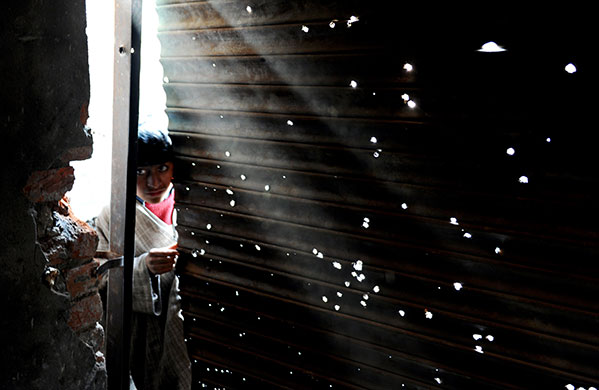 7 February 2010: Andrusa, India: A boy peeks inside a bullet-riddled shop