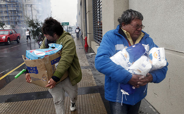 Chile earthquake: People carry goods during looting in Concepcion, Chile after an earthquake