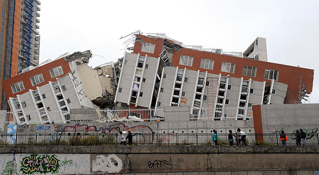 Chile earthquake: Passersby observe the remains of a destroyed building in Concepcion