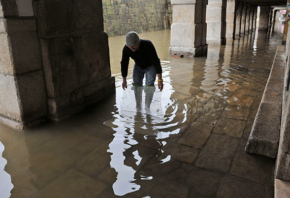 Storm damage in Europe: A Portuguese man amuses himself trying to catch fish trapped in floods 