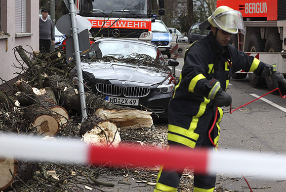 Storm damage in Europe: A fireman works next to a car damaged by a tree in Frankfurt