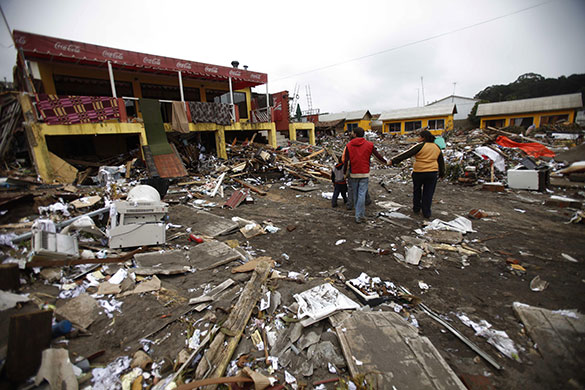 24 hours in pictures: Curanipe, Chile: People walk in a damaged area