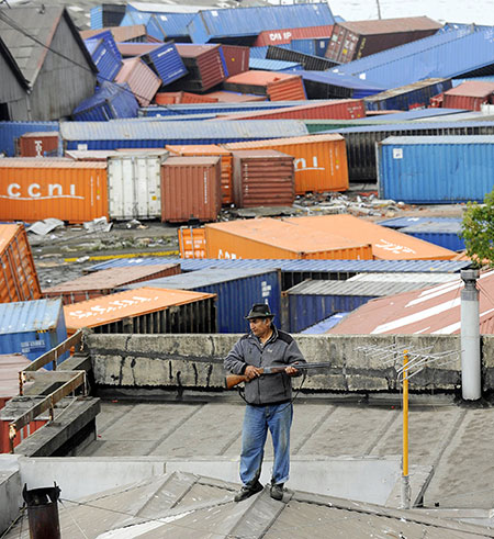 Tsunami damage: An armed man stands guard on his rooftop in Talcahunao