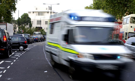 An ambulance drives at speed down a busy London street