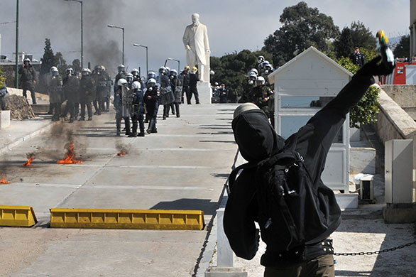 more strikes in greece: A protestor throws petrol bomb towards police