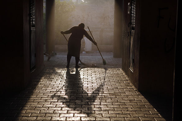24 hours in pictures: A woman sweeps an alley in Port-au-Prince, Haiti