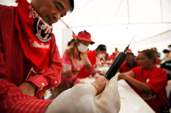 Thailand blood protest: Thaksin Supporter holds a syringe full of blood