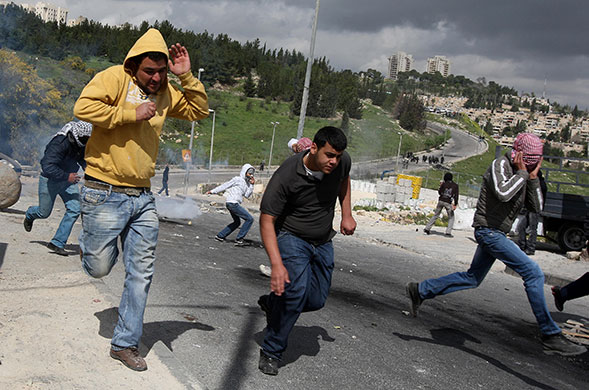 East Jerusalem protests: Palestinian demonstrators run as tear gas falls beside them