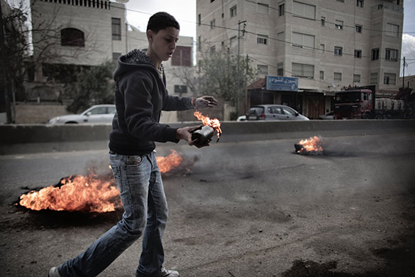 24 hours in pictures: Qalandia, West Bank: A Palestinian youth holds a petrol bomb