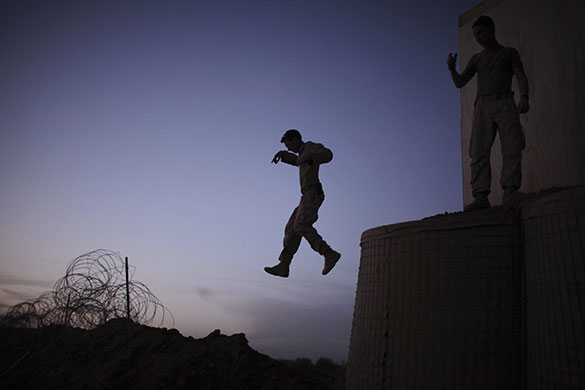 24 hours in pictures: A US Marine jumps from an observation point Marjah, Afghanistan