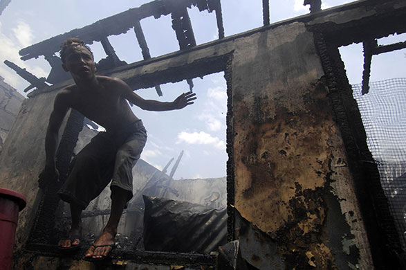 24 hours in pictures: Manila, Philippines: A resident inspects a gutted house after a fire 