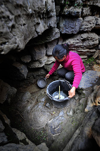 24 hours in pictures: A woman fetch water at the bottom of a well, China