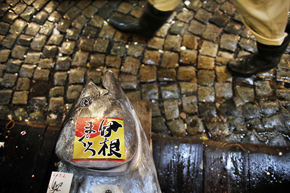24 hours in pictures: A fish dealer walks past a tuna at his stall in Tokyo