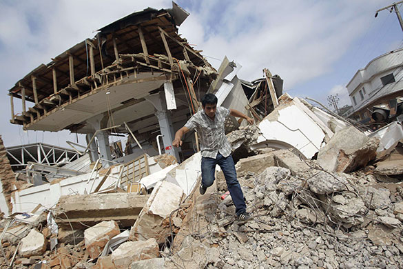 Chile after the quake: A resident climbs over debris after a major earthquake in Constitucion