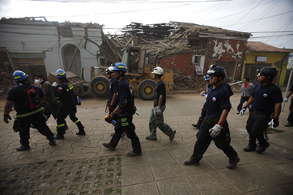 Chile after the quake: Rescuers walk past damaged buildings in Constitucion
