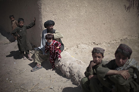 24 Hours in Pictures: An Afghan family waits outside their residence as US Marines search inside