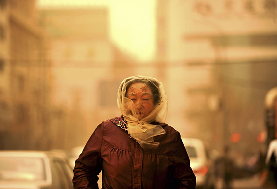 Sandstorms in China: a woman walks in the dust brought by standstorm in Lanzhou